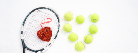 Heart of tennis balls and red heart on tennis racket on white snow winter background. Love Valentines day concept with tennis balls play. Flat lay, sport lifestyle, funny. horizontal, selectiva focusの写真素材