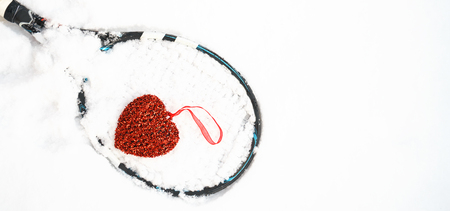 red heart on tennis racket on white snow winter background. I love you tennis player on Valentines day. concept with tennis play. Flat lay, sport, lifestyle, funny. horizontal, selective focusの写真素材