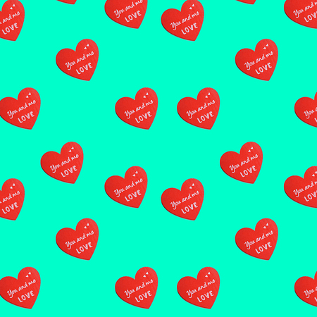 Red hearts with love text as pattern on pastel green  with copy space.の写真素材