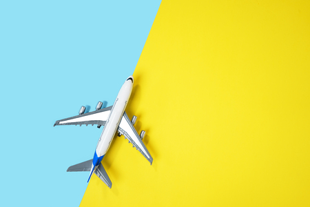Model airplane, plane on yellow and blue background. Directly above. Travel, vacation, summer concept. Top view, flat lay composition. Copy space.の写真素材