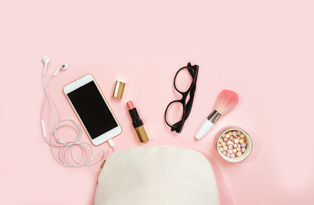 Top view female accessories: cosmetics, glasses, mobile phone, headphones, makeup on pink background. Valentines Day 8 March birthday office party outfit layout. Concept online shopping. Flat lay.の写真素材