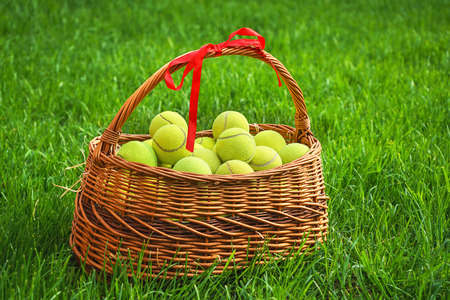 Tennis Easter with tennis balls in a basket on green grass. Selective focus, copy space.の写真素材