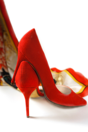 Fashion female red high heel shoes and accessories coral color silk neckerchief on white background, isolated. Christmas and Happy New Year, Valentines Day Party concept outfit. Copy space.の写真素材