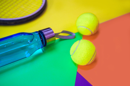 Tennis layout with tennis balls, racket, bottle of water on abstract different multicolored neon  with place for text.の写真素材