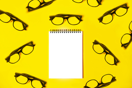 Notepad with trendy glasses on light yellowの写真素材
