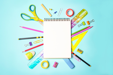 Back to school  with notepad, colorful pencils, square ruler, scissors, clips on pastel blue backdrop.の写真素材