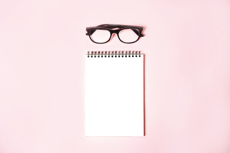 Notepad with trendy glasses on pastel pinkの写真素材