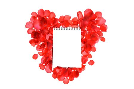 Red coral roses petals on heart shape and notebook isolated on white background. Love concept. Flat lay, top view, copy space. Valentines day, party, wedding, holiday, romance beauty conception.の写真素材