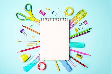 Back to school background with notepad, colorful pencils, square ruler, scissors, clips on pastel blue backdrop. Flat lay, top view, copy space.の写真素材