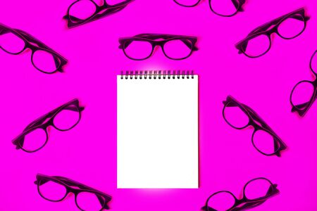 Notepad with trendy glasses on light pink background. Study, office layout. Flat lay, top view, copy space. Back to school, business concept.の写真素材