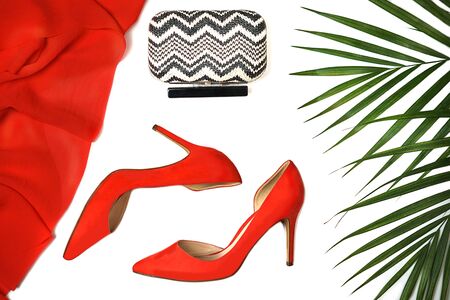 Top view party outfit red shoes accessories clutch tropical leaves on white background, isolated. Party Valentines Day Christmas Happy New Year wedding dinner layout. Flat lay, copy space.の写真素材