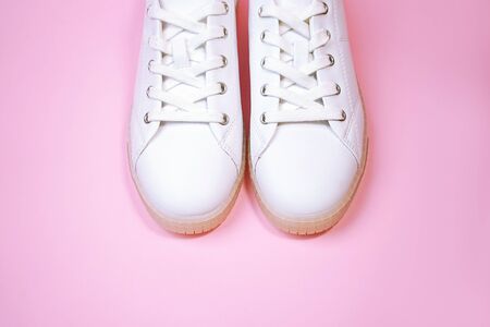 White sneakers are lying on a pastel pink background. Top view. Flat lay. Copy space.の写真素材
