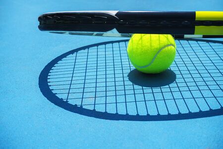 Summer sport concept with tennis ball and racket on blue hard tennis court. Top view, copy space. Blue and yellow.の写真素材