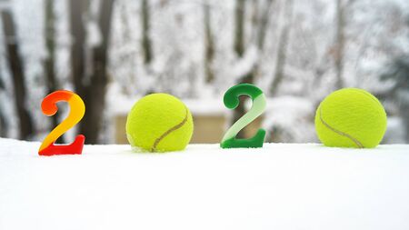 Tennis Christmas and 2020 New Year concept with tennis balls and candles with numbers on white snow, isolated. Top view, copy space. Winter sport healthy layout. Holiday conception. Banner size.の写真素材