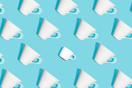 Coffee pattern of white ceramic cups for coffee on bright blue background. Pop art minimal flat lay style design, creative concept of diversity. Top view. Copy space. Banner.の写真素材