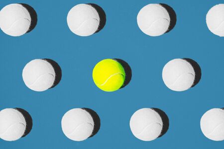 Creative composition made with yellow tennis ball and white balls on blue background. Sport tennis...