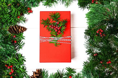 Christmas red gift box and fir tree branches with berries on whiteの写真素材