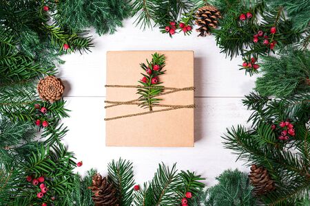 Christmas gift box and fir tree branches with red berries on whiteの写真素材