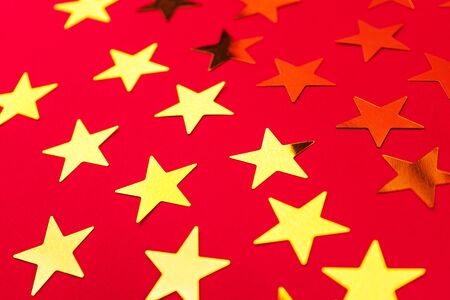 Bunch of gold stars on red pink background. Festive concept. Christmas, New Year, Birthday party holiday concept. Close up, flat lay, top view. Selective focus.の写真素材