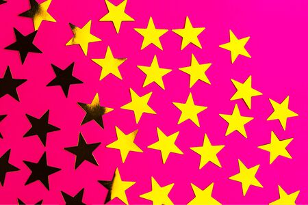 Bunch of gold stars on red pink background. Festive concept. Christmas, New Year, Birthday party holiday concept. Close up, flat lay, top view. Selective focus.の写真素材