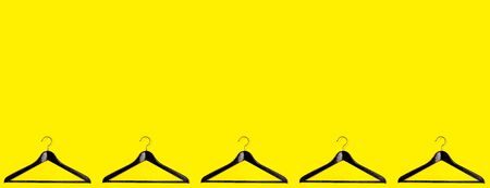 Fashion clothes hanger pattern on yellow background. Black Friday sale concept outfit with black clothes hangers. Flat lay, top view.の写真素材