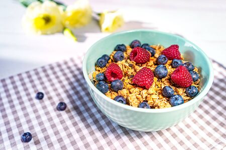 Bowl of homemade granola with fresh berries on gray wooden background. Top view, flat lay. Trendy...
