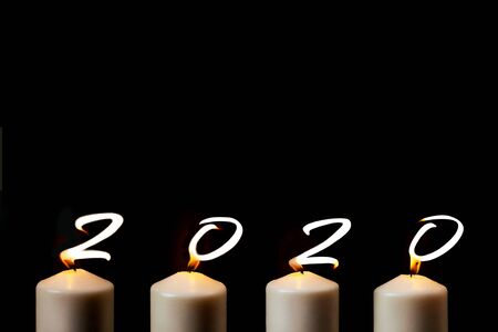 Marry Christmas and happy New Year. 2020 is written with candle flames on black background. Concept...