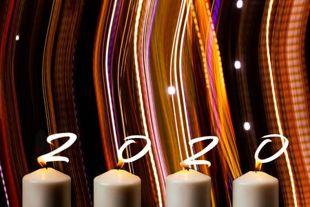Happy New Year 2020 is written with candle flames on party striped colorsの写真素材