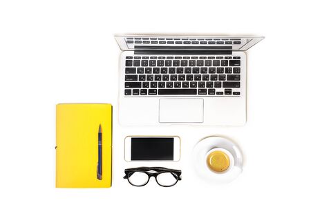 Workspace with laptop computer notebook, fashion glasses, cup of coffee, mobile phone and yellow notebook with pen on white background, isolated. Top view. Flat lay. Concept online shopping.の写真素材