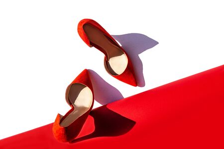 Red high heel shoes with shadow on coral color and white background. Fashion outfit abstract art layout. Top view, flat lay, copy space. Valentine's day modern concept.の写真素材