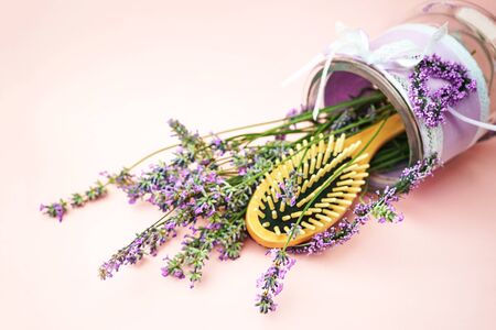 Wooden scalp and massage brush and hair comb with lavender flowers on pastel pinkの写真素材