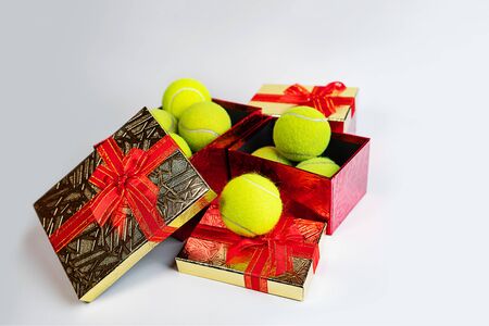 Tennis balls in holiday gift red boxes as present for Christmas, New Year, birthday. Copy space. Winter sport healthy layout. Holiday conception.の写真素材