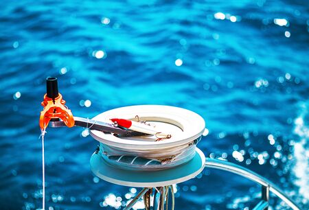 Fishing reel or rod reel, rod. Sailing yacht catamaran in the sea in Greece, turquoise waters of Aegean Sea near Athens. Famous travel sailing destination in Europe. Sailboat. Selective focuse.の写真素材