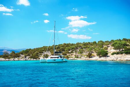 Sailing yacht catamaran boat with white sails on turquoise waters of sea. Yachting. Famous travel sailing destination: Greece, Caribbean. Sailboat.の写真素材
