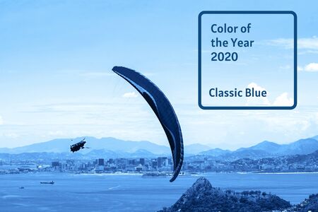 Blue color 2020 inscription. Gradient colors palette. A colorful parachute with skydiver on blue sky background. Extreme sport. Concept of holidays, tourism.の写真素材