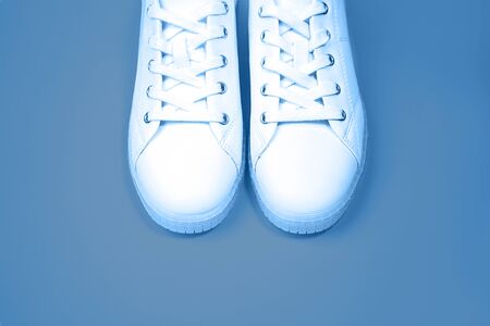 White sneakers are lying on a blue color background. Blue 2020 inscription.Top view. Flat lay. Copy space.の写真素材