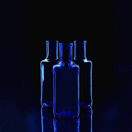 Empty classic blue color bottles isolated on dark background. Valentine's day, Birthday concept. Classic Blue color of the Year 2020 inscription.の写真素材