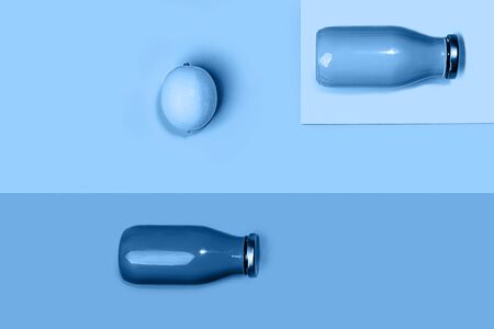 Bottles of multicolored juices or smoothies and lemon on trendy classic blue background. Flat lay, top view, close up. Minimal style. Classic Blue color of the Year 2020 inscription.の写真素材