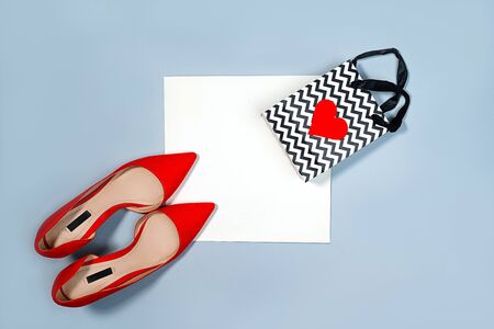 Valentines day concept with red woman shoes and gift bag with heart on pastel gray and white background. Party, Fashion layout. Top view. Copy space for text.の写真素材