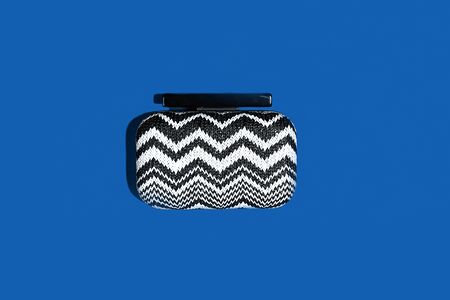 Composition of stylish clutch bag clutch on classic blue color backdrop. Trendy handbag with shadow. Classic Blue color 2020 concept. Main color trend. Copy space for text.の写真素材