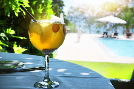 Cocktail glass in restaurant bar with sunny light on resort swimming pool and blue sea background. Party, travel summer concept.の写真素材