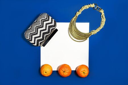 Female fashion layout with white paper sheet, orange tangerines and female accessories on classic blue color background. Christmas, Valentines day Party concept. Copy space. Classic Blue color 2020.の写真素材
