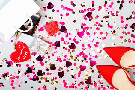 Christmas, Valentines day, birthday concept with red woman shoes, gift box and colorful confetti.の写真素材