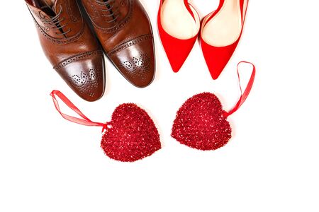Valentines day concept with man and woman shoes with two red hearts on white background, isolated. Party, Fashion. Top view. Copy space for text.の写真素材