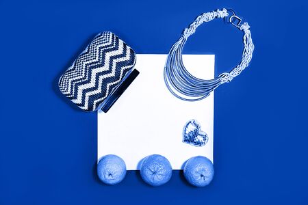 Female fashion layout with white paper sheet, orange tangerines and female accessories on classic blue colorの写真素材