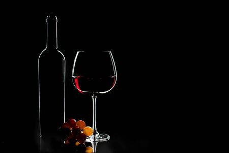 Elegant red wine glass, wine bottle and bunch of grapes on the dark background. Valentine's day, Birthday concept.の写真素材