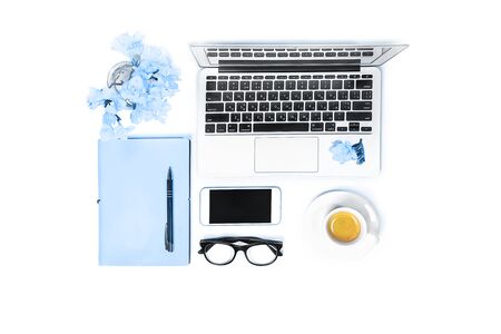 Women's workspace with laptop computer notebook, fashion glasses, cup of coffee, mobile phone and flowers on white background, isolated. Top view. Flat lay. Online shopping. Classic Blue color 2020.の写真素材
