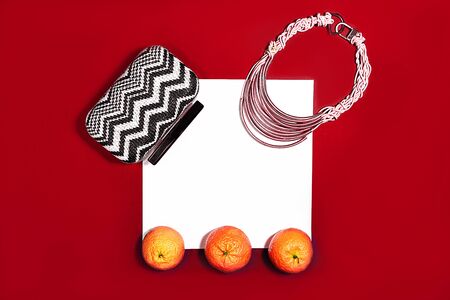 Female fashion layout with white paper sheet, orange tangerines and female accessories on classic red color background. Christmas, Valentine's day Party concept. Copy space.の写真素材