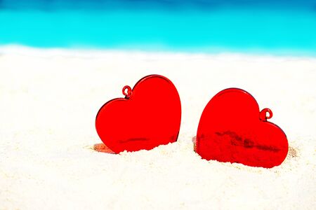 Red hearts on white yellow sand beach. Love concept for Valentine's Day or summer tropical vacation.の写真素材