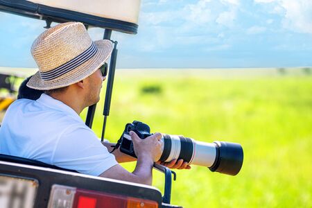 The man photographer takes a picture with professional camera from touristic vehicle on tropical...
